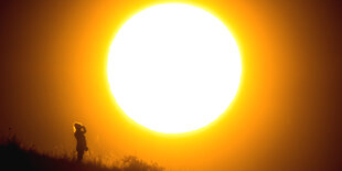 Frau steht vor untergehender Sonne