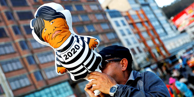 Ein Mann trägt eine Puppe durch La Paz, die Evo Morales in Gefängniskleidung zeigt