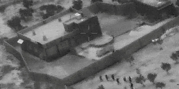 Ein verpixeltes schwarz-weißes Luftbild zeigt Soldaten beim Sturm auf ein Gebäude