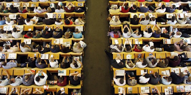 Sicht von oben auf Tischreihen, an denen Menschen sitzen