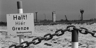 Ein Schild mit der Aufschrift "Halt! Hier Grenze" steht am Strand