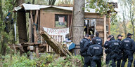 Eine Gruppe Polizisten steht vor dem Baumhaus mit einem Schild "Pappelapapp"