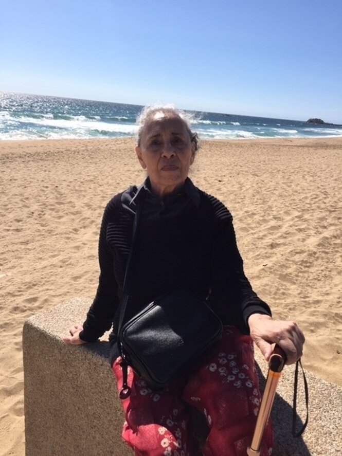 Eine Frau blickt am Strand in die Kamera