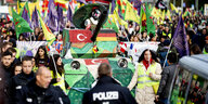 Demonstrierende mit kurdischen Fahnen, eine Panzeratrappe aus Pappe, Polizist*innen