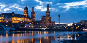 Lichter der Dresdner Altstadt spiegeln sich am Abend in der Elbe.