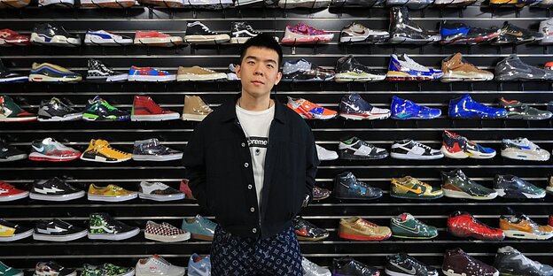 Der Gründer des chinesischen Konzerns Solestage steht vor einer Regalwand mit Sneakern