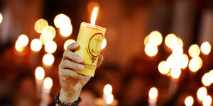 Hand hält Kerze während eines Gottesdienstaes zum gedenken an 39 Tote