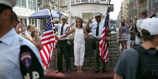 Zwei Soldatendarsteller stehen mit einer Touristin am Checkpoint Charlie