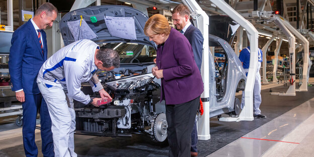 Bundeskanzlerin Angela Merkel (CDU) spricht, gemeinsam mit Herbert Diess (l), VW-Konzernchef, und Michael Kretschmer (CDU, r), Ministerpräsident von Sachsen, mit einem Arbeiter am Produktionsband für die Produktion des Elektroautos ID.3 zu. Das Fahrzeug g