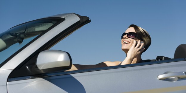 Frau im Cabrio telefoniert beim Fahren