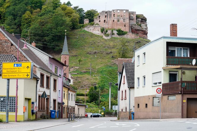 Häuser stehen in der pfälzischen Kommune Frankenstein vor der Burgruine Frankenstein.