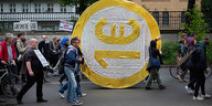 Menschen protestieren mit einer selbstgebastelten 1-Eueo-Münze