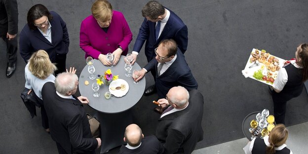 verschieden SPD- und CDU-Politiker*innen stehen um einen Tisch herum und feiern den Koalitionsvertrag
