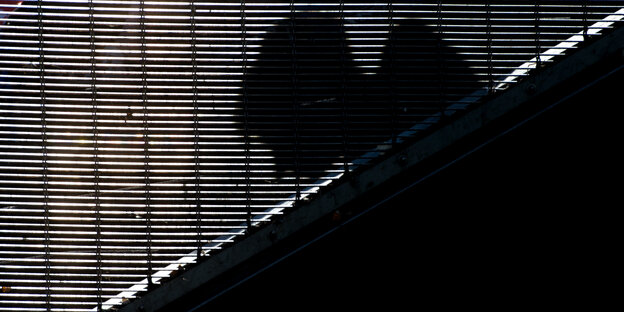 Die Silhouette eines Mannes zeichnet sich auf einem Gitter an einer Treppe in Hannover ab.