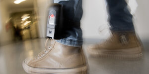 Ein Mann trägt eine elektronische Fußfessel.