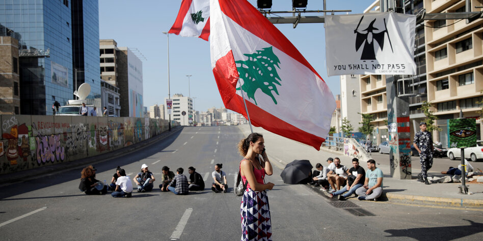 Demonstrantin mit großer Flagge auf leerer Autostraße