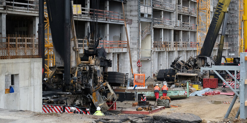 Von einem Brand beschädigte Kräne stehen an einer Baustelle.