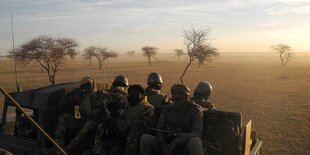 Soldaten aus Mali sitzen auf einem Militärfahrzeugnahe der Grenze zu Burkina Faso