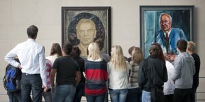 Eine Gruppe von Besucher*innen betrachtet POrtraits der ehemaligen Bundeskanzler Schröder und Kohl im Bundeskanzleramt