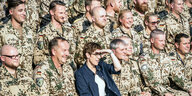 Annegret Kramp-Karrenbauer sitzt zwischen Soldaten und Soldatinnen