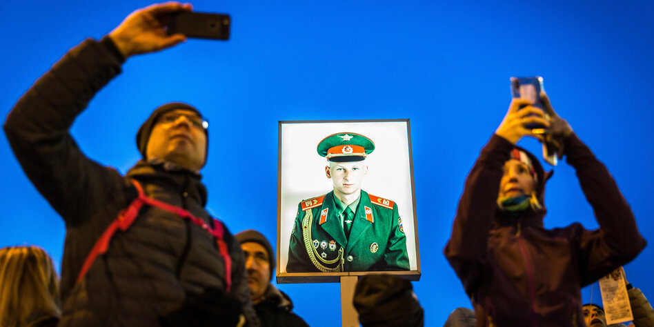 Menschen fotografieren sich mit ihrem Handy vor einem Soldatenbild