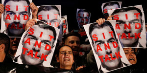 Frauen halten Plakate mit dem Gesicht von Pedro Sánchez, darauf steht "Sit and talk"