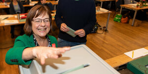 Eine Frau wirft einen Stimmzettel in eine Wahlurne