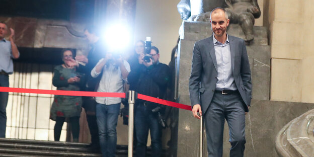 Belit Onay läuft als neuer Oberbürgermeister von Hannovereinen Teppe hinunter, im hintergrund Fotografen.