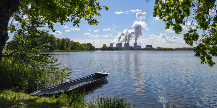 Im Hintergrund das Braunkohlekraftwerkes Jänschwalde, im Vordergrund ein See mit Boot