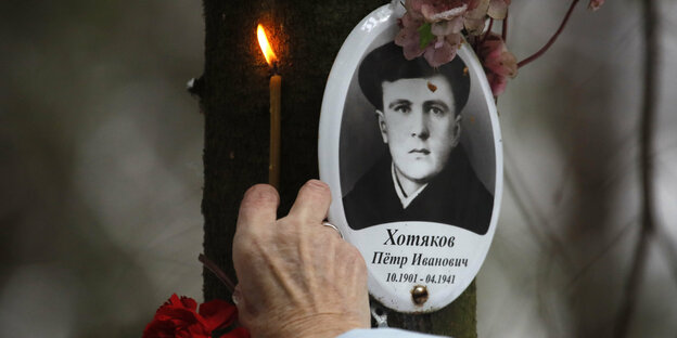 Gedenken mit einer brennenden Kerze an ein Opfer der Stalinschen Repressionen auf einem Friedhof in der Nähe von St. Petersburg Gedenken mit einer brennenden Kerze an ein Opfer der Stalinschen Repressionen auf einem Friedhof in der Nähe von St. Petersburg