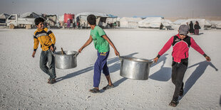 Syrische Kinder tragen in einem Flüchtlingslager, leere Töpfe