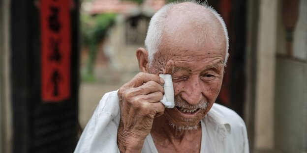Ein alter Mann wischt sich die Tränen ab