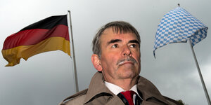 Gustl Mollath steht vor einer deutschen und einer bayrischen Flagge