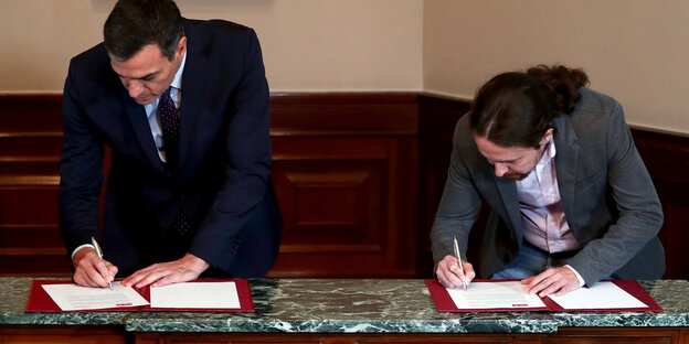 Pedro Sánchez und Podemos-Chef Pablo Iglesias unterschreiben eine Koalitionvereinbarung.