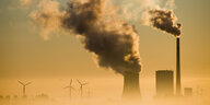 Ein Kohlekraftwerk und Windräder im Nebel