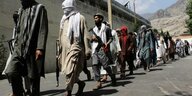 Bewaffnete Kämpfer der Taliban laufen eine Straße entlang.