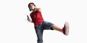 Ein Junge tanzt mit Kopfhörern vor neutralem Hintergrund.