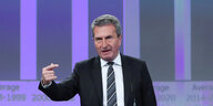 EU-Kommissar Oettinger steht vor einer Grafik-Präsentation und gestikuliert
