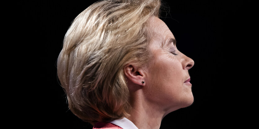 Ursula von der Leyen im Profil mit geschlossenen Augen vor neutralem Hintergrund.