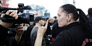 Frau auf einer Nazidemonstration schreit einen Kameramann mit erhobenen Zeigefinger an