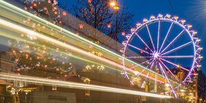 Ein hell erleuchteter Weihnachtsmarkt mit Riesenrad.