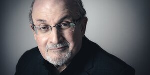 Salman Rushdie vor neutralem Hintergrund.