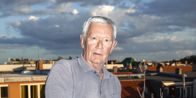 Ein Mann steht am Geländer eines Balkons vor abendlichem Himmel