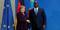 Angela Merkel und Felix Tshisekedi schütteln die Hände vor einer blauen Wand