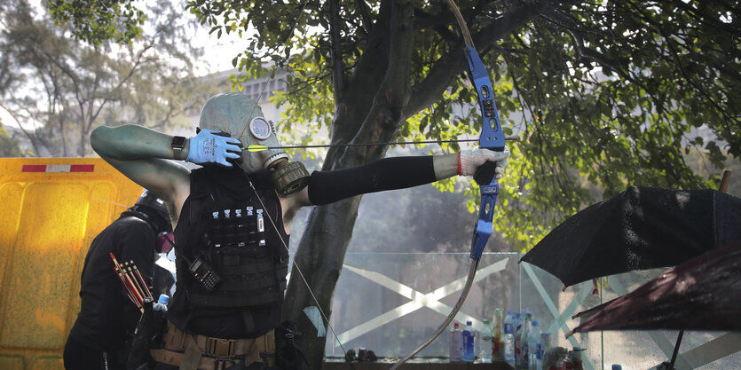 Ein Demonstrant mit Gasmaske und gespanntem Bogen