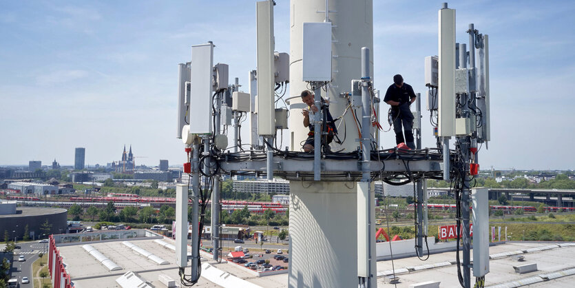 Zwei Techniker arbeiten an einem großen Mobilfunkmast