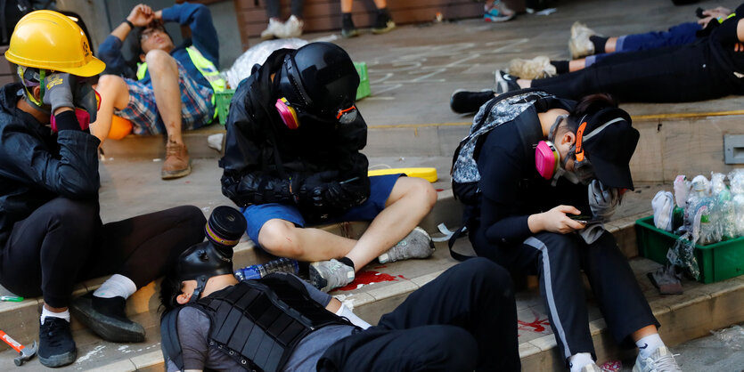 Demonstranten mit Masken und Helmen ruhen sich aus