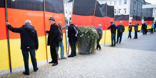 Anhänger des AfD-Politikers Björn Höcke stehen vor schwarz-rot-goldenen Transparenten