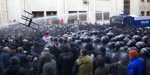 Die Polizei schießt mit einem Wasserwerfer auf einen Demonstranten vor dem Parlament in Tiflis