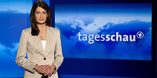 Die Tagesschausprecherin Linda Zervakis steht vor dem Logo der sendung